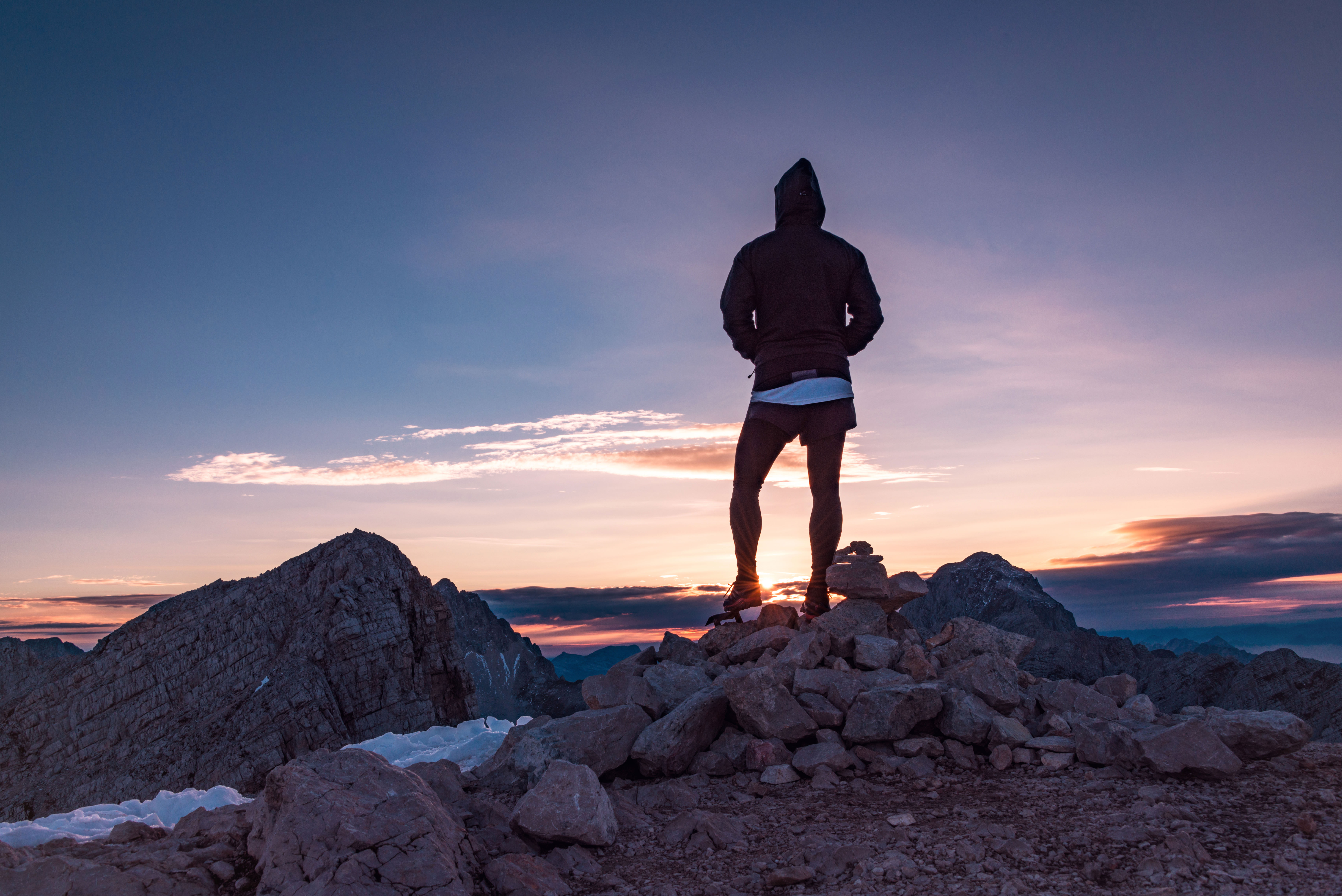 Male hiker in the vast mountain landscape at sunset. Beautiful mountain panorama in the evening in the Alps